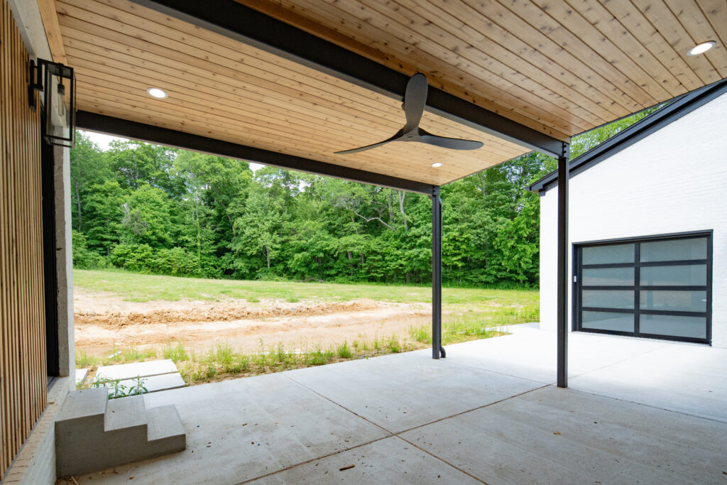 Stylish Louisville patio with wooden ceiling, concrete floor, and adjacent glass garage doors.