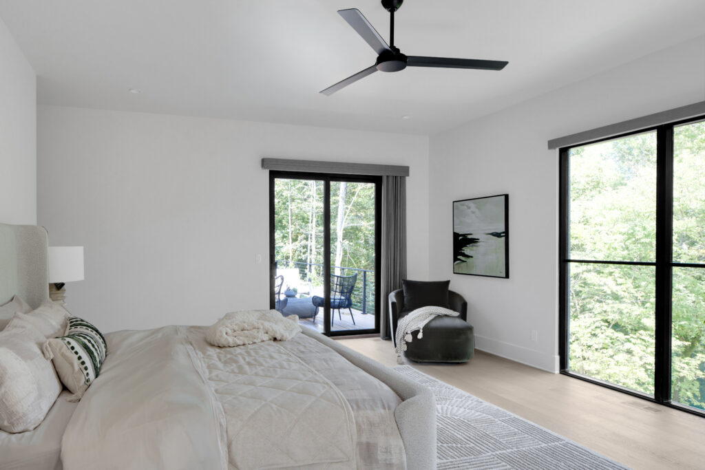 Louisville modern bedroom with balcony view, neutral tones, and striped pillows by top custom home builders.