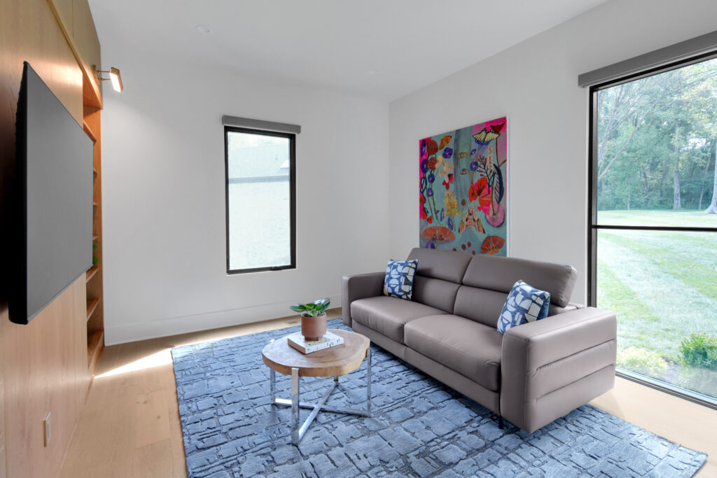 Louisville modern living room with gray couch, blue rug, and abstract art by top custom home builders.
