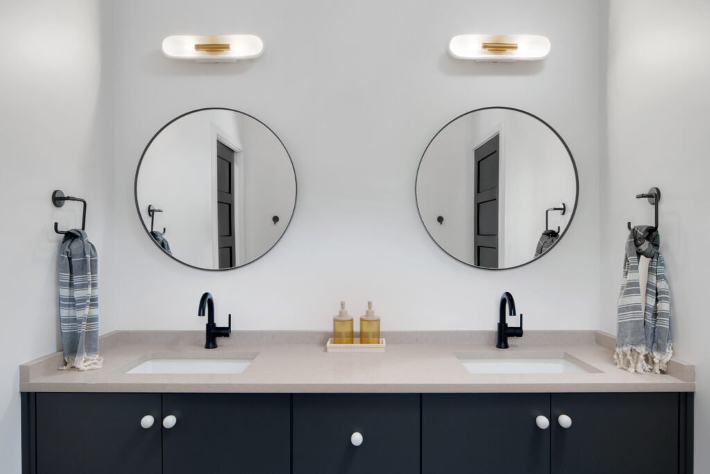 Louisville modern bathroom with dual mirrors, black faucets, and minimalist design by top custom home builders.