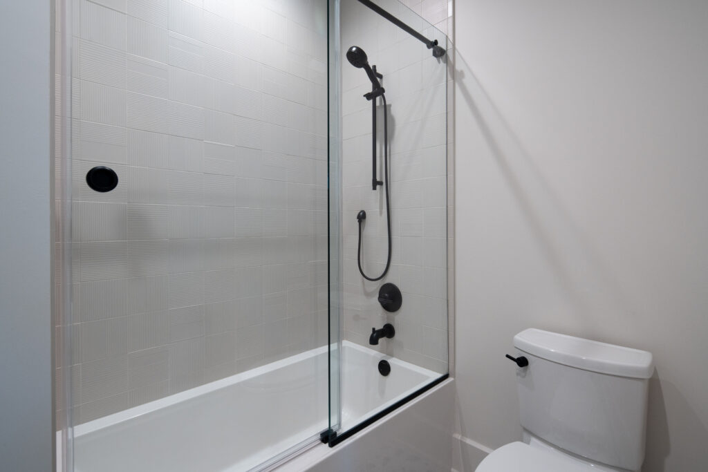 Louisville modern bathroom with white tub, glass shower, and black fixtures by top custom home builders.