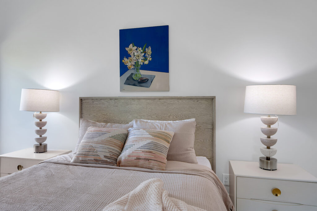 Louisville bedroom with neutral bed, textured pillows, and modern lamps by top custom home builders, Eldridge Company.