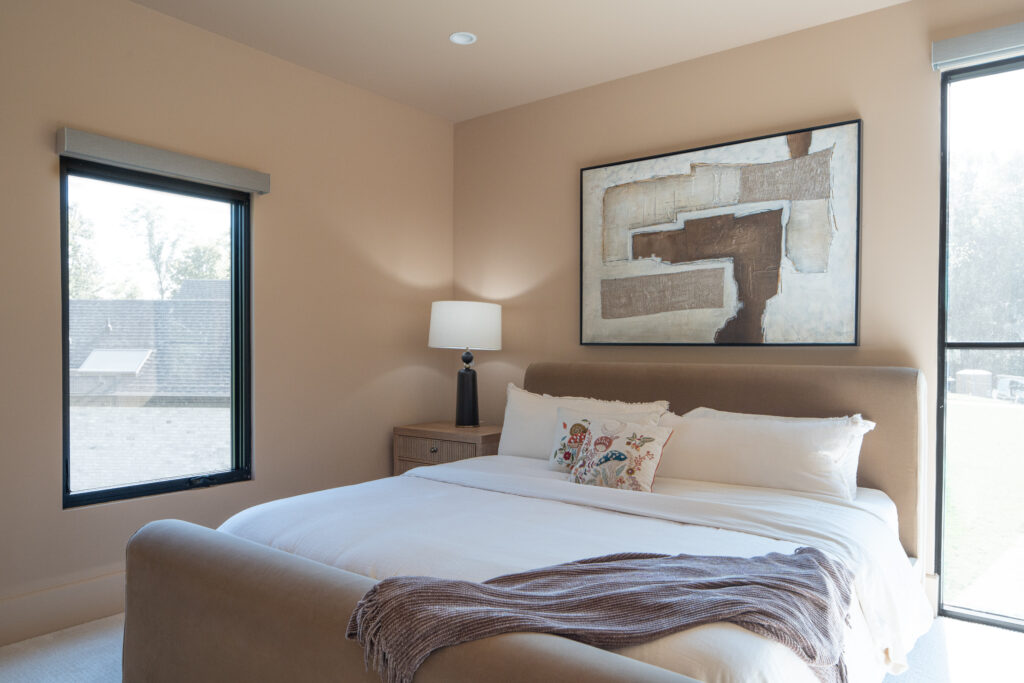 Louisville neutral bedroom with large bed, abstract art, and minimalist design by top custom home builders Eldridge Company.