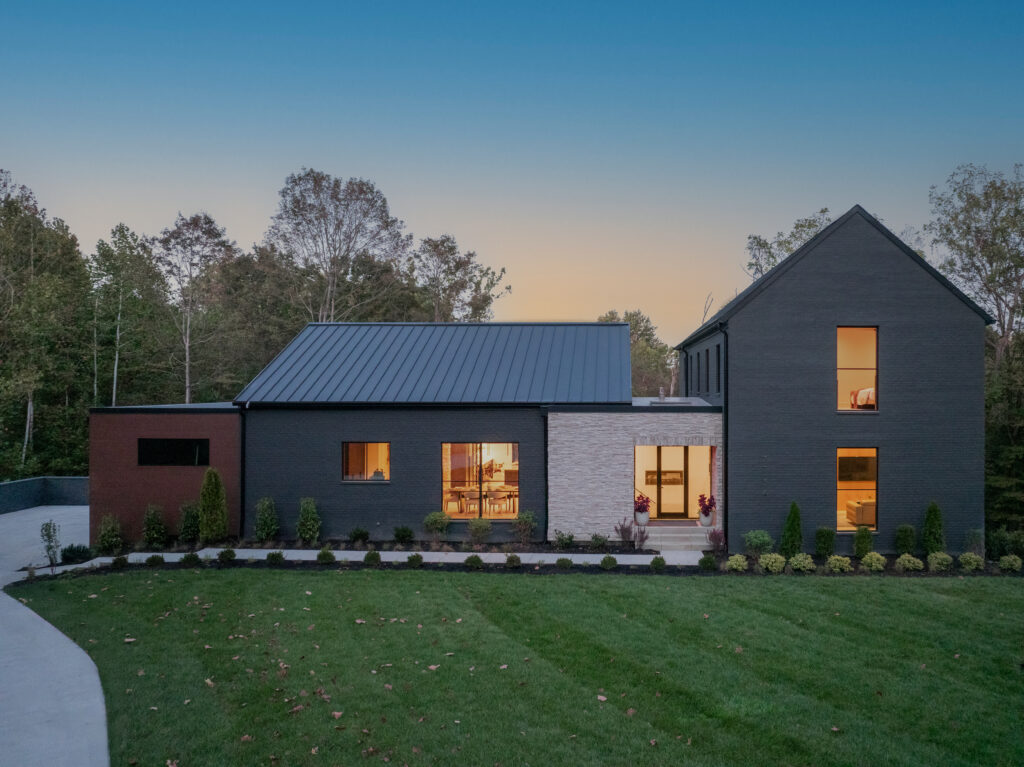 Modern Louisville custom-built home at Homearama 2025, Prospect KY, featuring brick and stone exterior with lit windows.