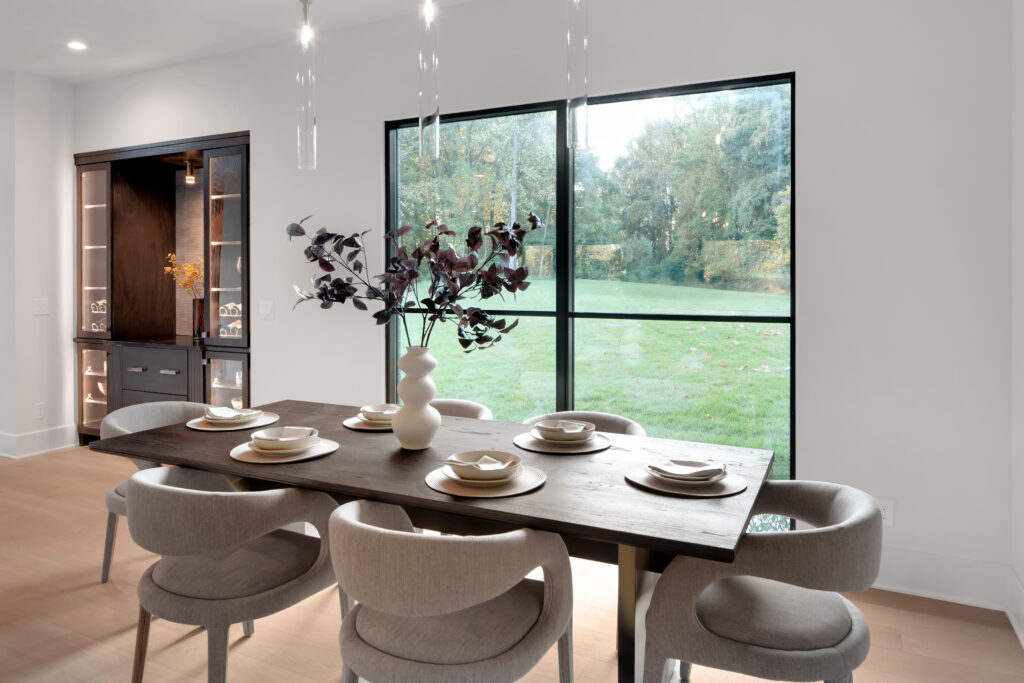 Woodbridge Place custom home dining room in Louisville Homearama 2025, featuring dark wooden table, cream chairs, and garden views.