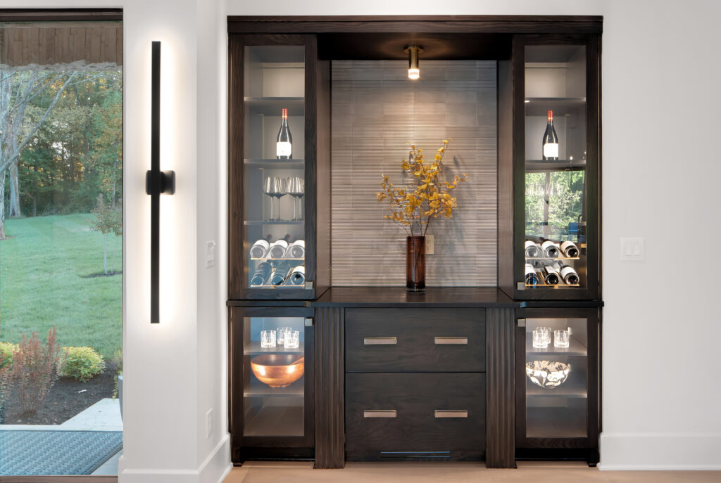 Modern Louisville home bar with dark wood cabinet and glass shelves by top custom home builders.