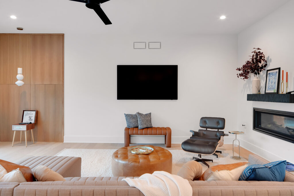 Modern Louisville living room with minimalist design, leather chairs, round ottoman, and sleek fireplace by top custom home builders.