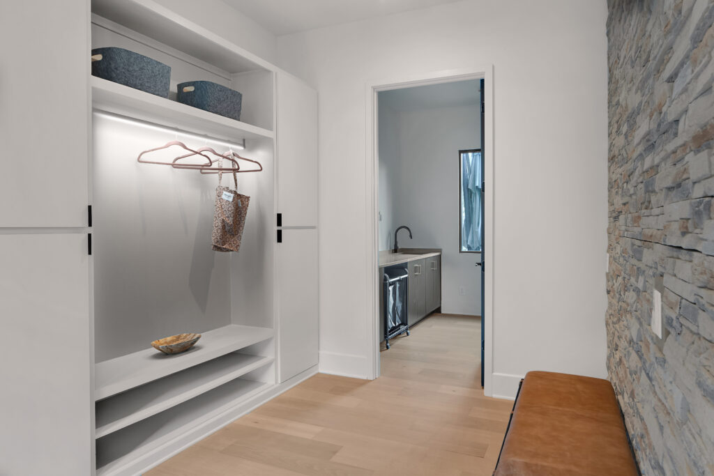 Minimalist Louisville laundry room with stone accent wall and open shelving by top modern home builders.