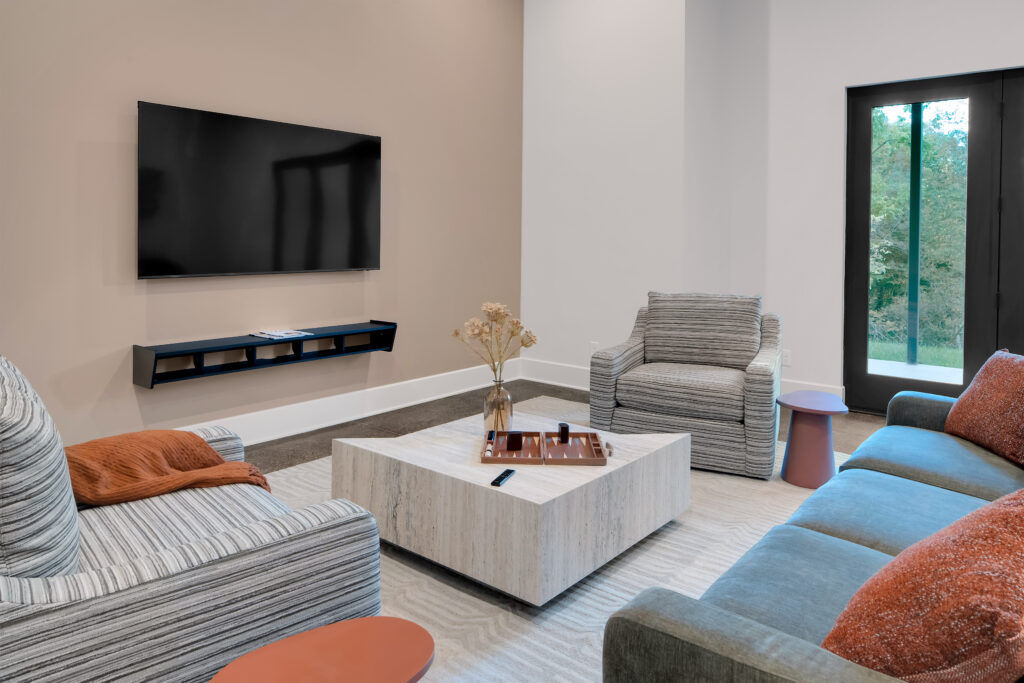 Louisville modern living room with gray armchairs, blue sofa, and marble table by top custom home builders Eldridge Company.
