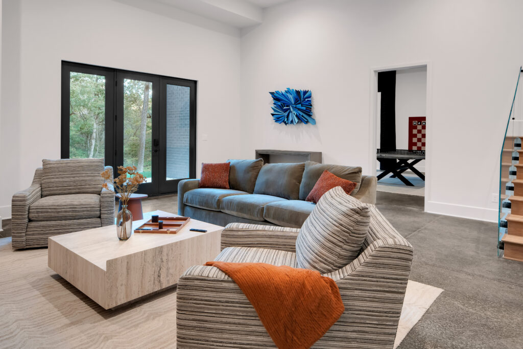Louisville modern living room with gray sofa, striped armchairs, and blue artwork by top custom home builders Eldridge Company.
