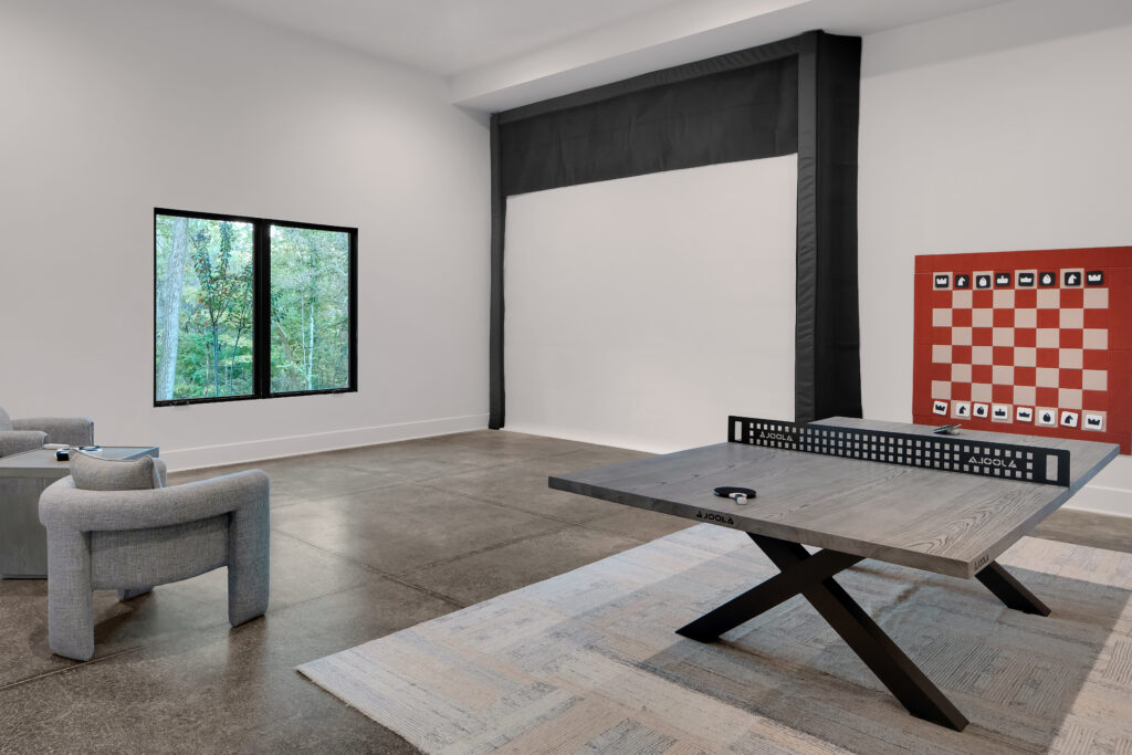 Louisville minimalist game room with ping pong table, red chess board, and greenery view by top custom home builders.