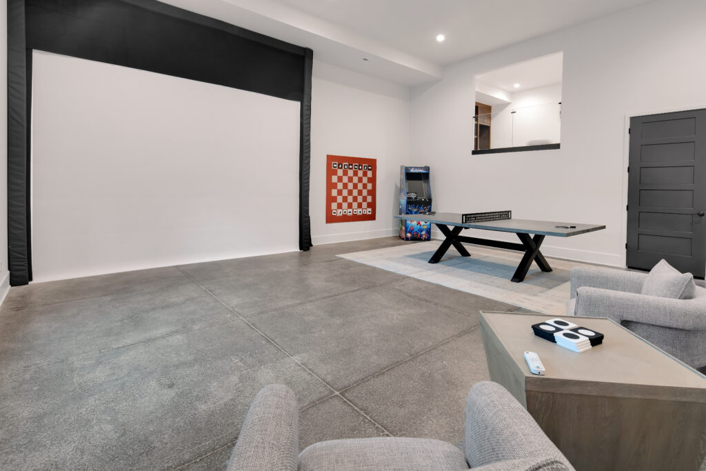 Louisville modern entertainment room with large screen, arcade, and ping pong by top custom home builders.