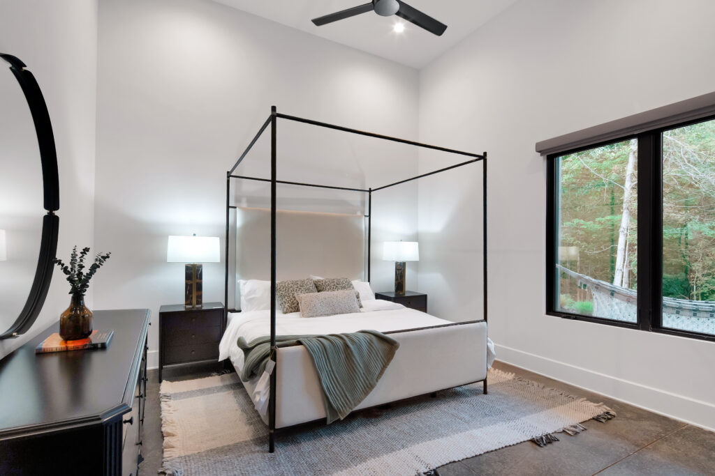 Louisville modern bedroom with four-poster bed, green accents, and large window by top custom home builders.