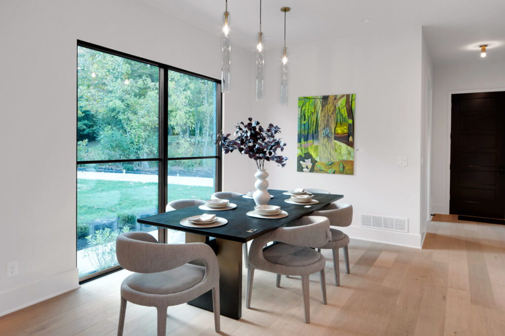 Elegant Louisville dining room with black table and pendant lights by leading custom home builders.