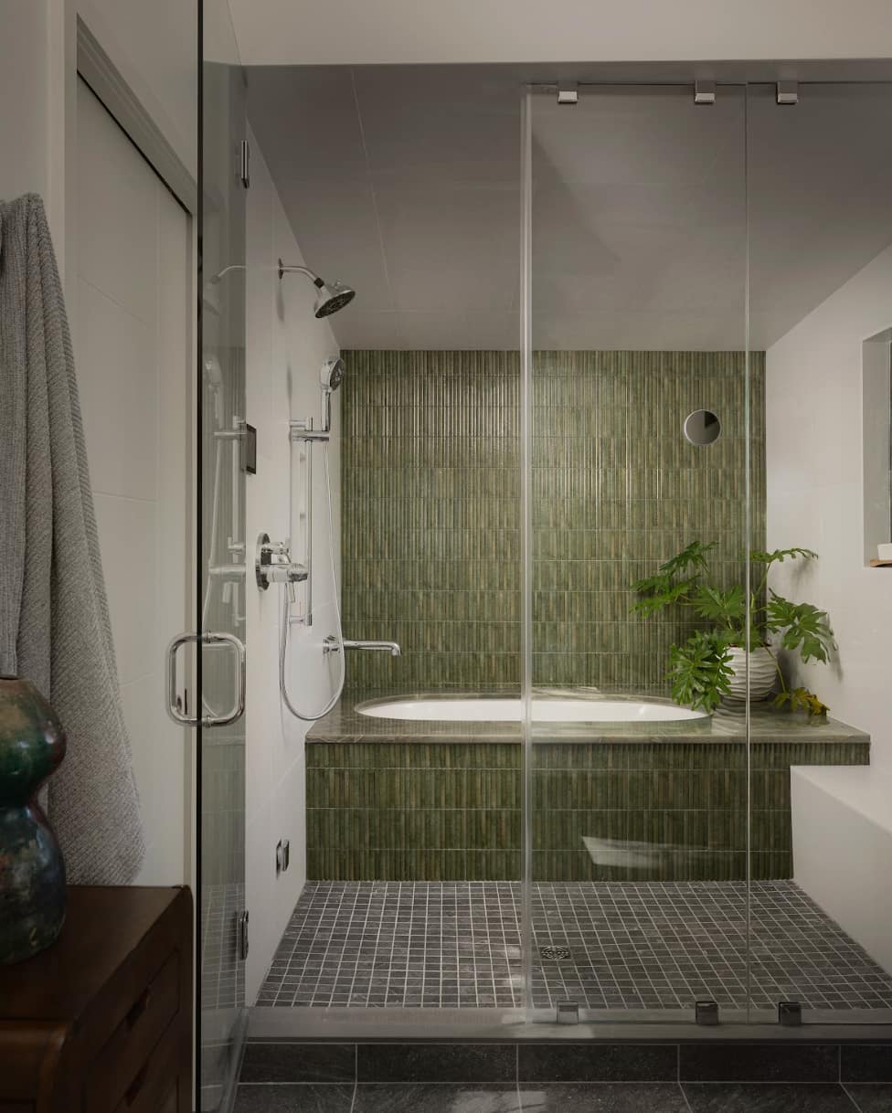 Green tiled shower room in custom built home with bathtub enclosed in shower room.